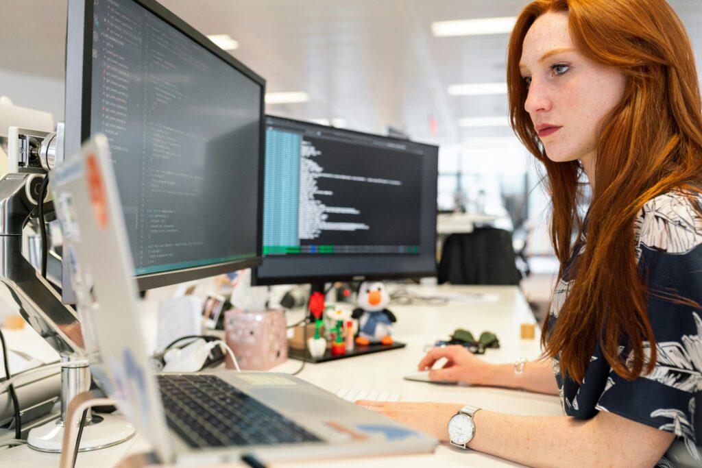 pexels-photo-3861958-3861958 A focused female software engineer coding on dual monitors in a modern office.